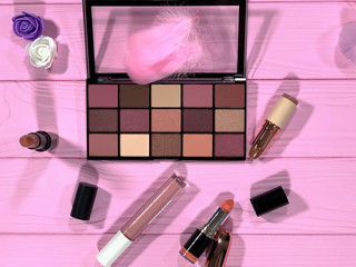 Eye shadow palette for make-up, lipstick. Decorative cosmetics on the table. Pink background with place for text.