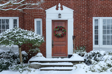 Wall Mural - Front door of  house with Christmas wreath and snow covered trees