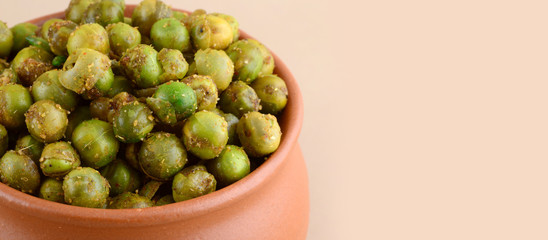 Spiced fried green peas {chatpata matar} Indian snack. Dried salted green peas in clay pot.