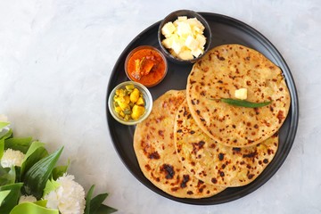 Wall Mural - Indian Food - Aloo Paratha or Indian Potato stuffed Flatbread. Served with butter for breakfast, pickle and masala potatoes among with Indian Tea or masala chai.  with copy space.