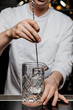 Bartender prepairing a cocktail at the bar stirring a drink in a mixing glass with a bar spoon