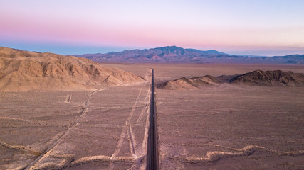 Poster - Panoramic drone view of a straight desert road at sunset near Death Valley heading towards Las Vegas Nevada