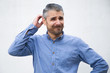 © Mangostar - Positive thoughtful man scratching head and thinking. Grey haired young man in blue casual shirt posing isolated over white background. Choice concept