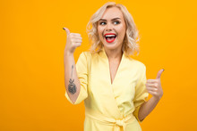 Cheerful Young Woman With Short Blonde Hair Smiles And Recommends Something Isolated On Orange Background