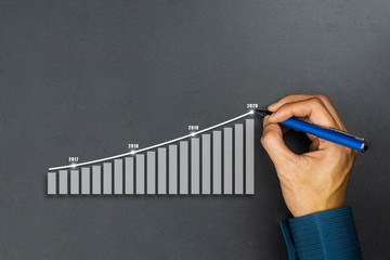 Businessman drawing graphics line year growing graph. Describe the organization's management plan or Company and development guidelines. Depicts business growth up continuity plan until 2020.