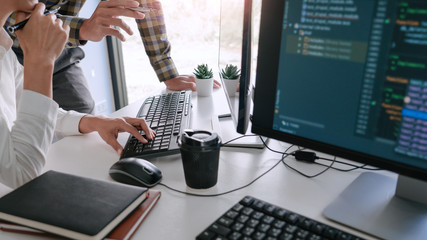 Young startup Programmers Sitting At Desks Working On Computers screen for Developing programming and coding to find solution to problem on New Application.