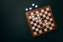 Top View Of Checkers On Wooden Checkerboard Isolated On Black With Copy Space
