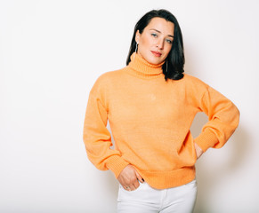 Studio portrait of beautiful brunette woman wearing orange pullover, posing on white background