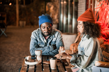 Wall Mural - Young couple resting in street cafe with hot drink