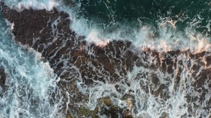 Wall Mural - Waves beat against a rocky shore, aerial view