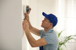 © New Africa - Technician installing CCTV camera on wall indoors