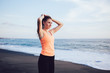 © GalakticDreamer - Young smiling sportswoman making ponytail on sea beach
