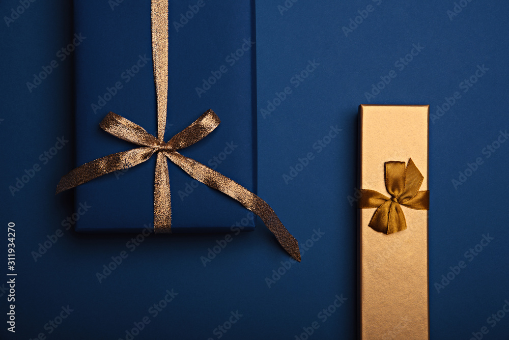 Two gift boxes wrapped in classic blue and golden paper with a gold ...