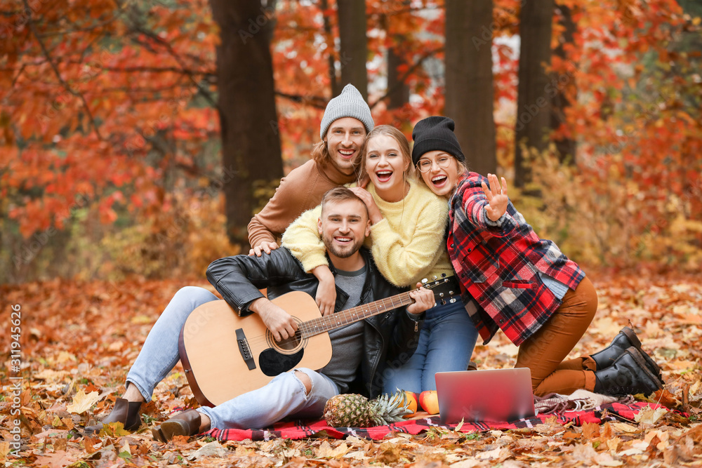 Happy young friends resting together in autumn park