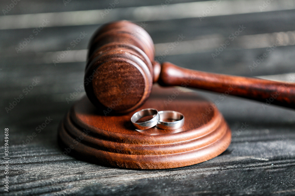 Judge's gavel and rings on wooden background. Concept of divorce