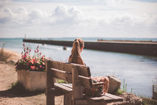 Woman Sitting On A Bench And Looking At The Sea