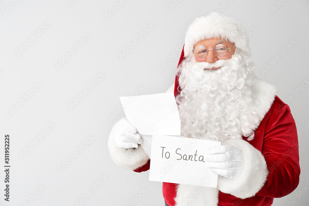 Santa Claus with letter on light background