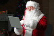© Pixel-Shot - Santa Claus with laptop in room decorated for Christmas