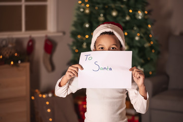 Wall Mural - Cute African-American boy with letter to Santa Claus on Christmas eve at home