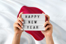 Japan New Year Concept. Woman Holding Happy New Year Sign With Hands On National Flag Background. Celebration Theme.