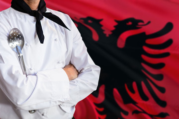 Albania domestic food concept. Professional chef in white uniform is standing with metal spatula. Copy space for text.