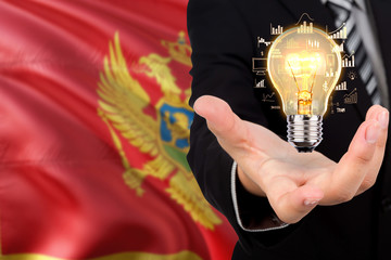 Montenegro creativity concept. Businessman with a light bulb in his hand on national background. Innovation and technology theme.