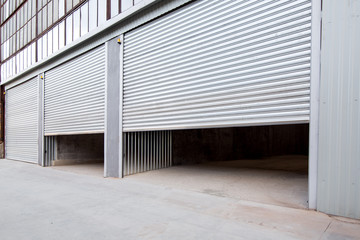 Wall Mural - gray steel shutter of an industrial garage with gray concrete porch, side view nobody.