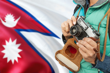 Wall Mural - Nepal photographer concept. Close-up adult woman holding retro camera on national flag background. Adventure and traveler theme.