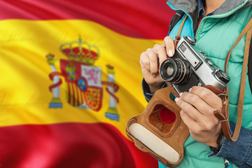 Wall Mural - Spain photographer concept. Close-up adult woman holding retro camera on national flag background. Adventure and traveler theme.