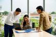 © kajonsakt - Young Asian businesswoman and businessman partners while working together discussing new project presentation before work business meeting withcomputer on wooden table background in office.