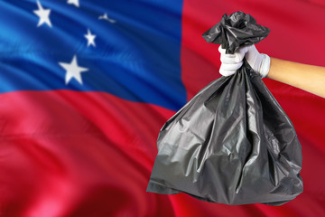 samoa environmental protection concept. the male hand holding a garbage bag on national flag backgro