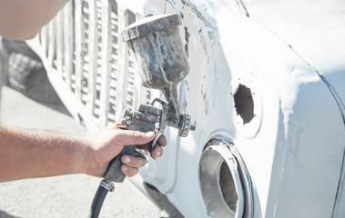 Wall Mural - Spray gun in the hand of a painter. Painting car details