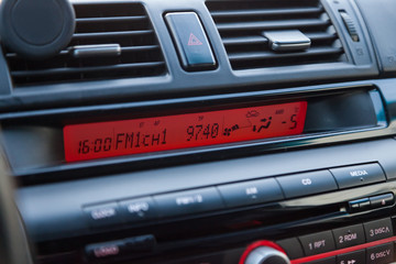 Wall Mural - Display of the multimedia system of the car is glowing in red at night indicating the radio station, air conditioning temperature and other tools to monitor the condition of the vehicle