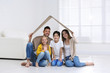 © New Africa - Happy family sitting under cardboard roof at home. Insurance concept