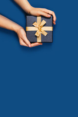 Wall Mural - Gift box with surprise in a female hands on classic blue background. Flat lay, top view, place for text.