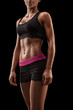 © USM Photography - Beautiful sexy female slim tanned body. Cheerful attractive young fitness woman in black top and black shorts isolated over black background