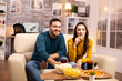 © DC Studio - Beautiful young couple watching TV and eating fast food takeaway