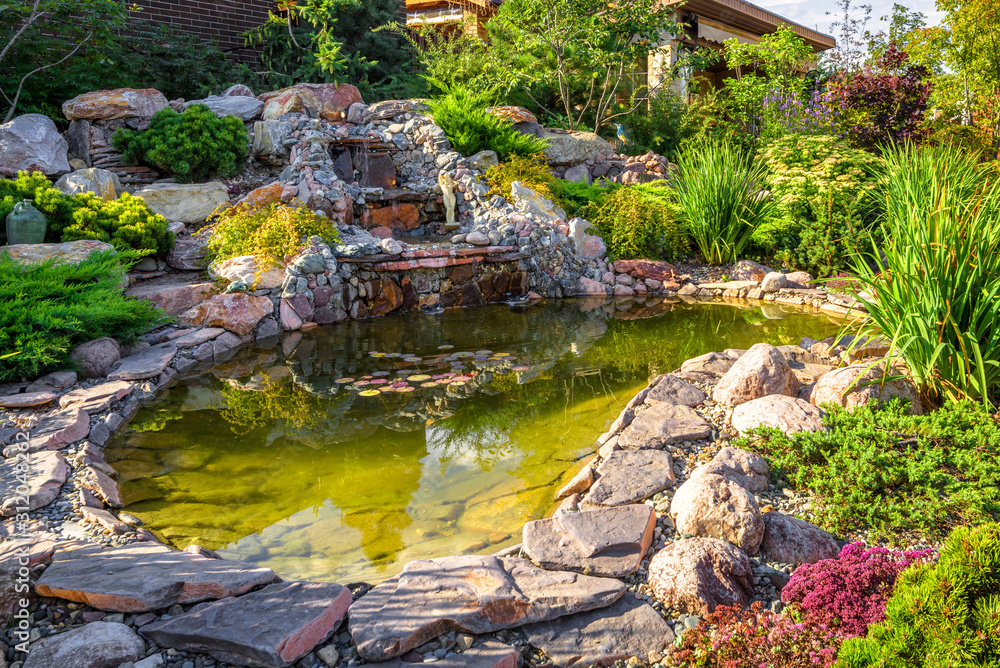 Landscape design of home garden close-up. Beautiful landscaping with small pond and waterfall. - obrazy, fototapety, plakaty 
