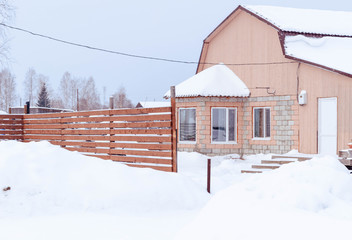 village in winter in the snow on a sunny day. street of wooden houses road at houses near the forest, no people.