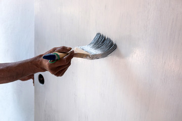 male hand painting wall with Paint brush.Close up of painter hand painting a wall with Paint brush.