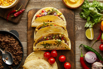 Canvas Print - Top view of traditional mexican tacos with organic ingredients on wooden background