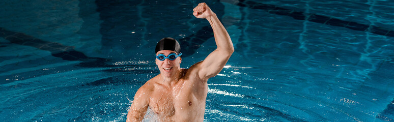 panoramic shot of excited swimmer in goggles celebrating triumph