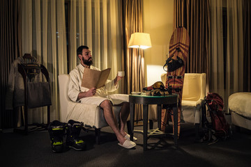 A male snowboarder has a rest in the hotel room in the evening