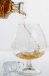 Decanting cognac into a brandy snifter on white background