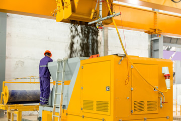 an automatic concrete mixer loads the finished mixture into a device for the formation of hollow core slabs under the control of a male engineer.