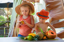 Photo Of Funny Siblings. Couple Of Happy Children With Smiling Face Eating Exotic Tropical Fruits. Healthful Food, Natural Picnic On Luxury Resort. Healthy Lifestyle On Summer Family Holiday With Kids