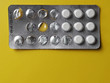 Consumption of drugs or tablets. Used blister with empty cells and white pills on yellow background. Warning of overdose. Medicine and healthcare close-up photo.