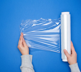 hand hold a large roll of wound white transparent film for wrapping food