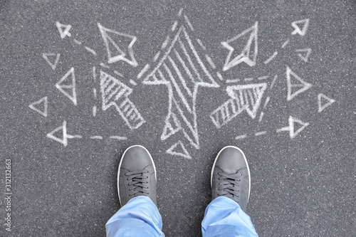 Person standing on asphalt road near arrows pointing in different directions, top view Tableau sur Toile