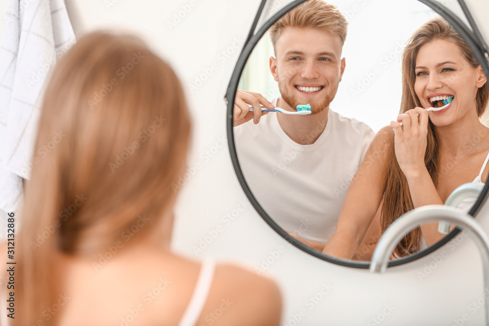 Young couple brushing teeth at home